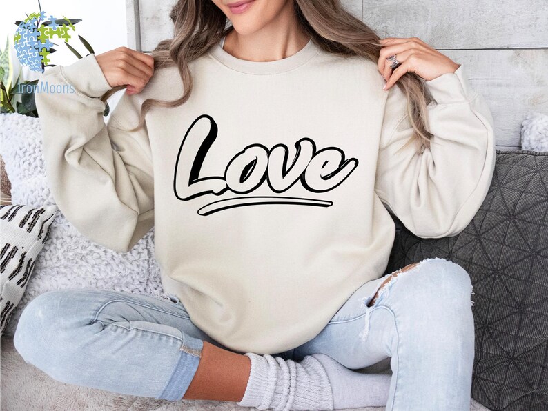 May include: A cream colored sweatshirt with the word "Love" printed in black on the front.