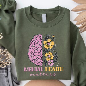 May include: Green sweatshirt with a pink and yellow brain with flowers and the text "Mental Health Matters".