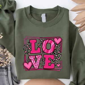 May include: A green sweatshirt with a pink graphic of the word "LOVE" with leopard print and hearts.