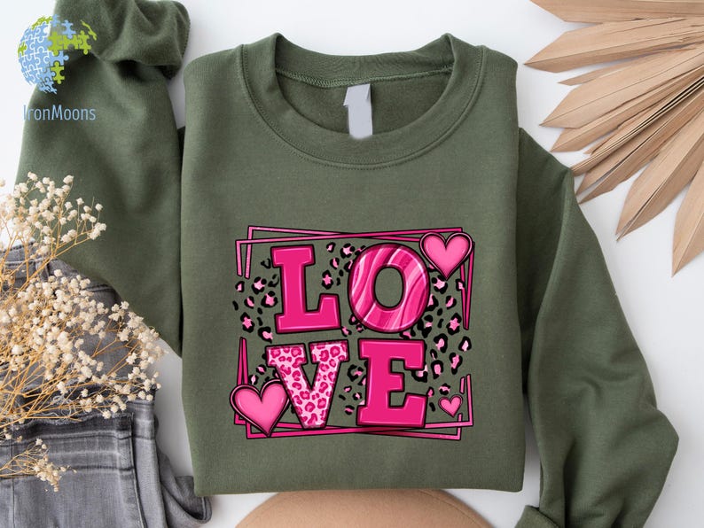May include: A green sweatshirt with a pink graphic of the word "LOVE" with leopard print and hearts.