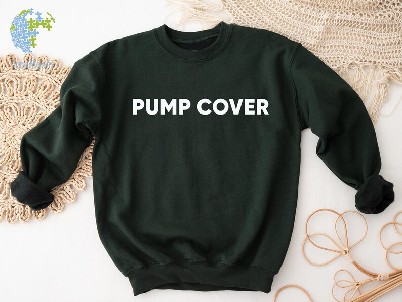Pode incluir: Um moletom verde escuro com as palavras "PUMP COVER" impressas em branco no peito. O moletom tem mangas compridas e gola redonda. A imagem &eacute; tirada de um &acirc;ngulo ligeiramente elevado.