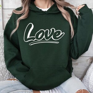 May include: A dark green hooded sweatshirt with a white "Love" graphic on the front.