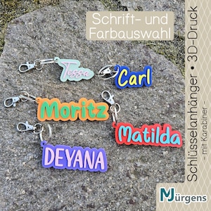 Könnte beinhalten: Eine Auswahl an farbenfrohen Namens-Schlüsselanhängern mit Karabinerhaken. Die Schlüsselanhänger zeigen Namen wie "Tessa", "Carl", "Moritz", "Matilda" und "Deyana" in verschiedenen Farben. Das Bild enthält auch den Text "Schrift- und Farbauswahl" und "Schlüsselanhänger • 3D-Druck".