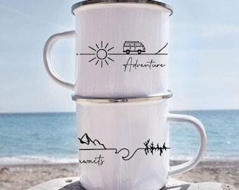 May include: Two white enamel camping mugs stacked on top of each other. The top mug has a black graphic of a sun, a camper van, and the word "Adventure". The bottom mug has a mountain range, a wave, trees, and the word "awaits".