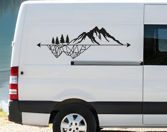 May include: A black vinyl decal applied to the side of a white van. The design features a mountain range and three pine trees above a horizontal line, with a geometric, angular pattern forming the base beneath the line and arrows at each end.