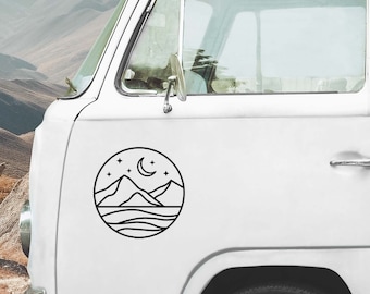 May include: Black circular decal featuring a mountain range, crescent moon, and stars. The design is affixed to the side of a white van. The decal's minimalist style is suitable for outdoor enthusiasts.