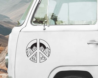 Puede incluir: Una pegatina con el símbolo de la paz en blanco y negro con un diseño de paisaje de montañas y árboles. La pegatina está adherida al lateral de una furgoneta blanca, con un fondo de montañas.