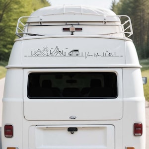 May include: A white van features a black line art decal on its rear window. The design includes mountains, a sun, pine trees, a small camper van, birds, a tent, and the cursive text Van life, all connected by a single horizontal line.