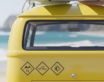 Op de afbeelding: Een gele vintage bus met surfplanken op het dak, geparkeerd bij het strand. De bus heeft drie zwarte ruitvormige stickers met berg-, golf- en zonmotieven. De surfplanken zijn pastelgroen en roze.