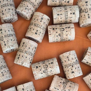 May include: A collection of cork bottle stoppers with various sayings printed on them, including "Goes Well With", "Anywhere", and "The Original".