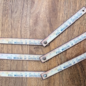 May include: Four vintage wooden rulers with a white background and black text that reads "FULL MEASURE OF SATISFACTION".