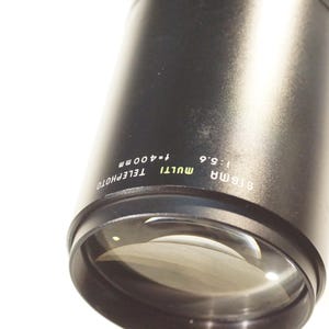 May include: A black telephoto lens with the text "G135MM MULTI 1:5.6 74-400MM TELEPHOTO" printed on the side.