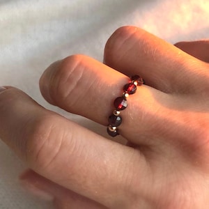 May include: A gold ring with a band of small red beads.