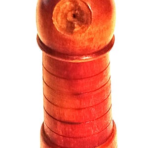 May include: A wooden pepper mill with a rounded top and a small knob. The body is cylindrical with horizontal grooves. The pepper mill is a reddish-brown color.