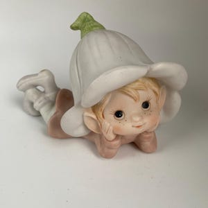 May include: A white ceramic mug with a black handle and the text "But First, Coffee" in a bold, black font. The mug is set against a blurred background, suggesting a cozy setting. The mug appears to be approximately 4 inches tall.