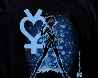 May include: Black t-shirt featuring a blue graphic of a character in a sailor uniform, with a heart-shaped symbol and Japanese text. The design is set against a blue speckled background. A pair of black and white sneakers are in the foreground.