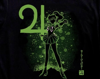 May include: Black t-shirt featuring a green graphic of a character with the number 24 and Japanese text. The character is in a fighting pose. Black and white Converse sneakers are in the foreground.