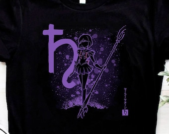 May include: Black t-shirt featuring a purple graphic of a character with a staff, accompanied by Japanese text and symbols. The design includes a splash effect. A pair of black canvas sneakers with white soles and laces are in the foreground.