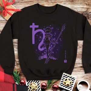 Puede incluir: Sudadera negra con cuello redondo con un gráfico morado de un personaje con un bastón, texto japonés y un símbolo. El diseño incluye un efecto de salpicaduras moradas y un símbolo de Saturno.