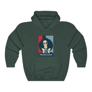 May include: A dark green hoodie with a graphic of a skeleton character with a top hat and the word "MUSICIAN" printed below. The graphic is in a red, white, and blue color scheme.