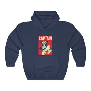 K&ouml;nnte beinhalten: Marineblauer Hoodie mit einer roten und wei&szlig;en Grafik eines springenden Comic-Charakters mit dem Wort "CAPTAIN" dar&uuml;ber.