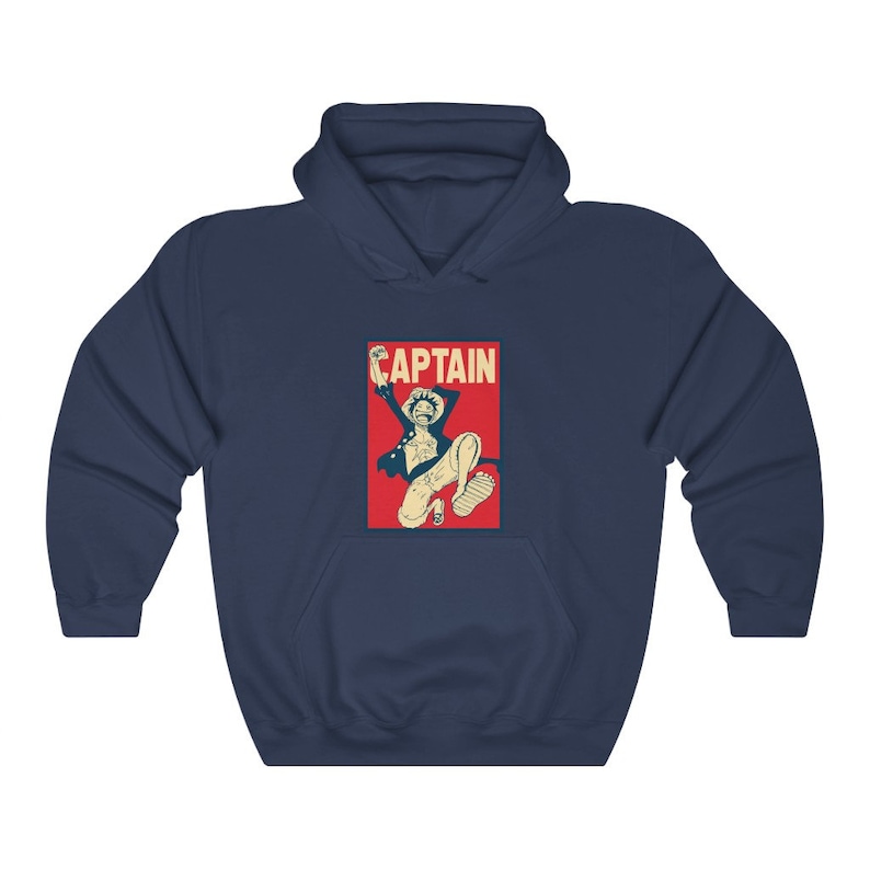 K&ouml;nnte beinhalten: Marineblauer Hoodie mit einer roten und wei&szlig;en Grafik eines springenden Comic-Charakters mit dem Wort "CAPTAIN" dar&uuml;ber.