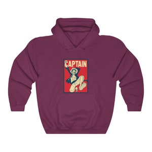 K&ouml;nnte beinhalten: Ein maroonfarbener Hoodie mit einem Vintage-Poster-Druck eines Anime-Charakters, der springt, mit dem Wort "CAPTAIN" in wei&szlig; auf rotem Hintergrund.