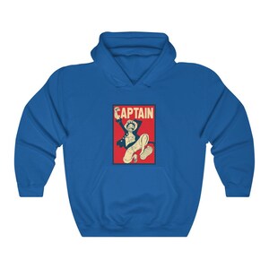 K&ouml;nnte beinhalten: Ein blauer Hoodie mit einer roten und wei&szlig;en Grafik eines springenden Comic-Charakters mit dem Wort "CAPTAIN" dar&uuml;ber.