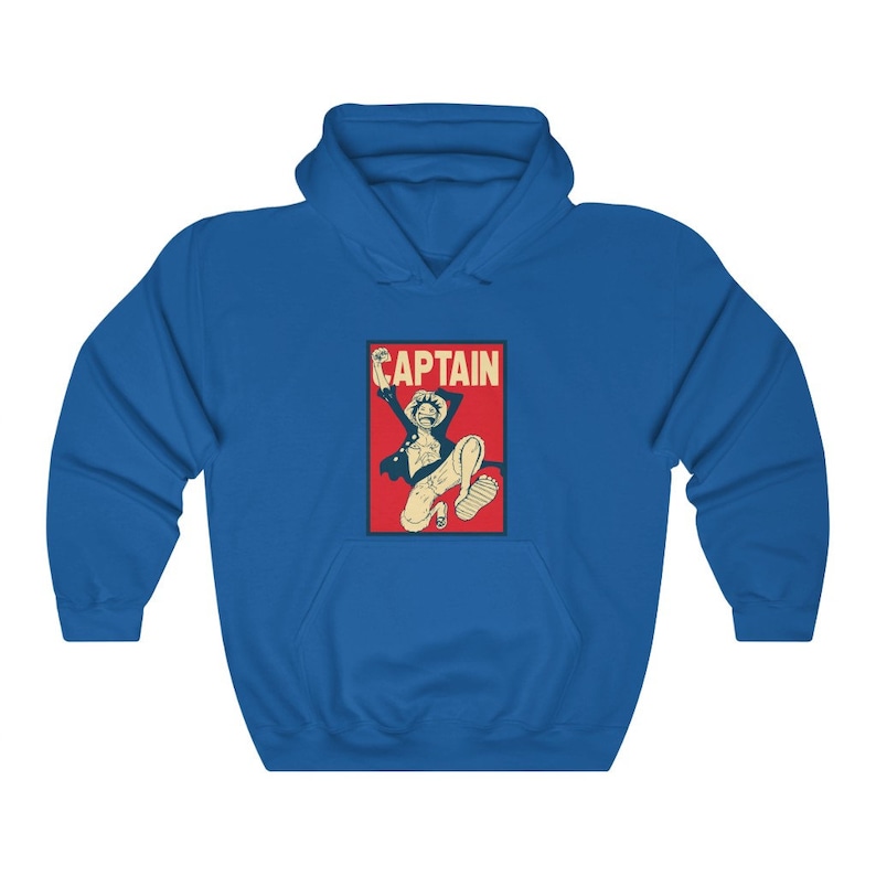 K&ouml;nnte beinhalten: Ein blauer Hoodie mit einer roten und wei&szlig;en Grafik eines springenden Comic-Charakters mit dem Wort "CAPTAIN" dar&uuml;ber.