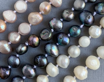 May include: Three strands of pearls in different colors: white, pink, and iridescent black. The pearls are all irregular in shape and have a slightly matte finish.