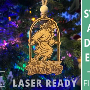 May include: Wooden Christmas ornament featuring a laser-cut design of a figure walking, with the text "Walk This Way." The ornament is suspended by a string and a small wooden bead. The background is a Christmas tree with colorful lights. The words "LASER READY FILES" are also visible.