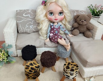 Könnte beinhalten: Ein Puppenhaus-Wohnzimmerset mit einem weißen Weiden-Sofa, einem braunen Teddybär und vier kleinen Hocker. Die Hocker haben verschiedene Stoffbezüge, darunter schwarz, braun, grau und Leopardenmuster.