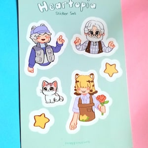 以下が含まれることがあります： 「Heartopia」と書かれたステッカーセット。キャラクターと星の漫画イラストが描かれています。青いベストを着た人、おじいさん、猫、バラを持った人、黄色の星のステッカーが含まれています。