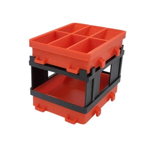 May include: A two-tiered storage container with a bright orange top and bottom, and a black support structure. The top section is divided into six compartments. The container is designed for organizing small items.