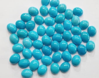 May include: A collection of oval-shaped turquoise cabochons, a type of gemstone, in various sizes. The stones are a vibrant blue colour and have a smooth, polished finish.