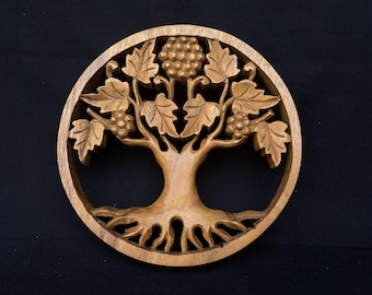 May include: A circular wooden wall hanging with a carved tree of life design. The tree has intricate branches, leaves, and grapes. The roots are also carved in detail.