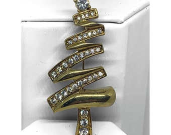 May include: A gold-tone Christmas tree brooch with clear rhinestones. The tree is made of a twisted metal design with a star at the top.