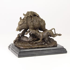 Può includere: Scultura in bronzo raffigurante un cinghiale attaccato da cani da caccia. La scultura è montata su una base di marmo nero. Il cinghiale è in piena azione, con cani che saltano e mordono. Un cane più piccolo è sulla schiena del cinghiale.