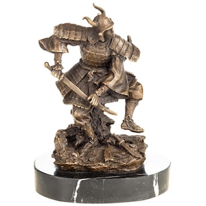May include: Bronze samurai warrior figurine, in a dynamic pose with two swords. The detailed sculpture features traditional armour and helmet, mounted on a black and white marble base. A collectible item.