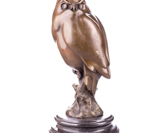 May include: A bronze owl sculpture perched on a branch, mounted on a dark marble base. The owl has detailed feathers and a focused gaze. The sculpture is a decorative item.