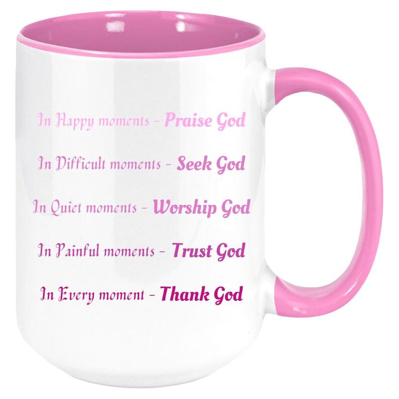 May include: White ceramic mug with a pink interior, handle, and rim. The mug features the text "In Happy moments - Praise God, In Difficult moments - Seek God, In Quiet moments - Worship God, In Painful moments - Trust God, In Every moment - Thank God."