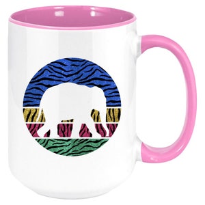 May include: White ceramic mug with a pink rim and handle. The mug features a colourful graphic of an elephant silhouette in a circle with a zebra print background.