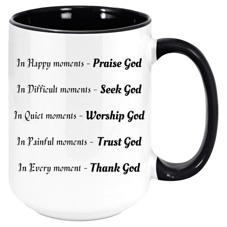 May include: White ceramic mug with a black interior and handle. The mug features the text "In Happy moments - Praise God", "In Difficult moments - Seek God", "In Quiet moments - Worship God", "In Painful moments - Trust God", and "In Every moment - Thank God".