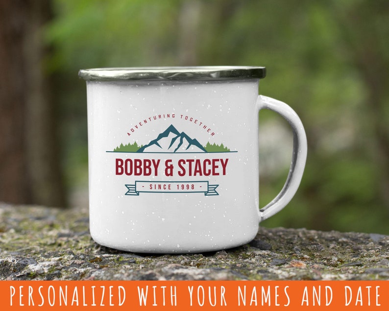 May include: White enamel camping mug with a black and green mountain design and the text "Adventuring Together Bobby & Stacey - Since 1998 - "