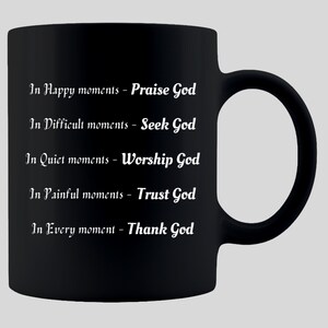 May include: Black ceramic mug with white text. The text reads: "In Happy moments - Praise God, In Difficult moments - Seek God, In Quiet moments - Worship God, In Painful moments - Trust God, In Every moment - Thank God."