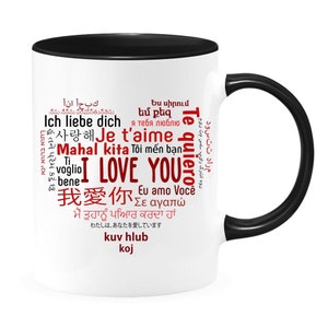 May include: White ceramic mug with a black rim and handle. The mug features a red heart-shaped word cloud with the words "I Love You" in English and various other languages, including "Te quiero", "Je t'aime", "Ich liebe dich", and "Mahal kita".