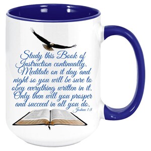 May include: White ceramic mug with a blue rim and handle. The mug features a blue and white image of an open book with an eagle flying above it. The text on the mug reads "Study this Book of Instruction continually. Meditate on it day and night so you will be sure to obey everything written in it. Only then will you prosper and succeed in all you do. Joshua 1:8"