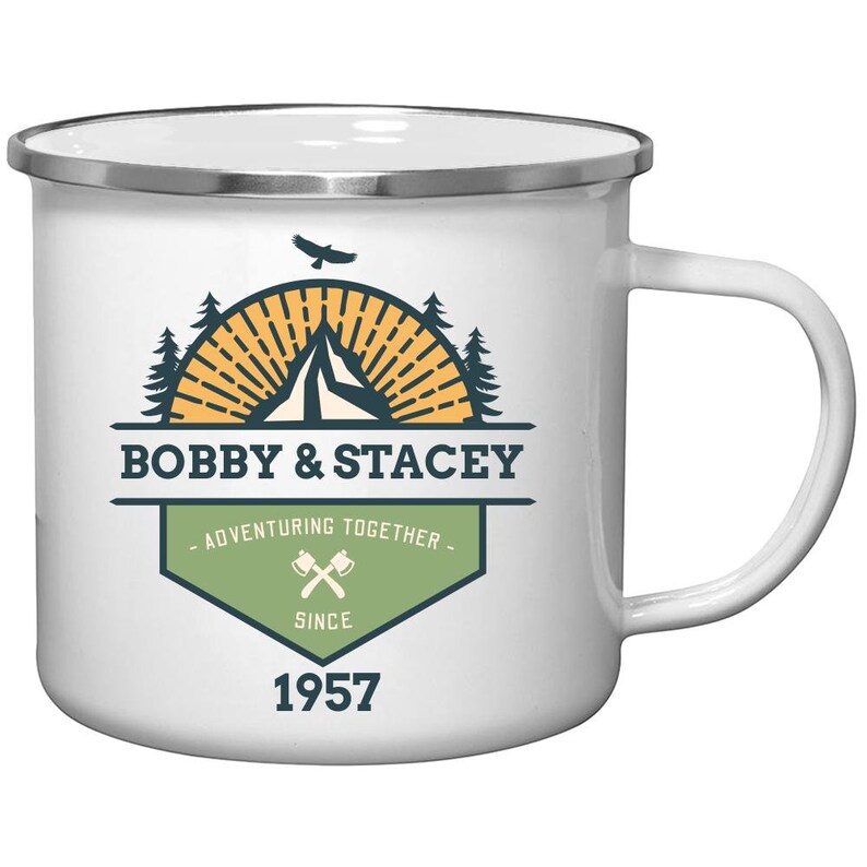 May include: White enamel camping mug with a silver rim and handle. The mug features a graphic with the text "BOBBY & STACEY" above "ADVENTURING TOGETHER SINCE 1957". The graphic includes a mountain, trees, and a bird.