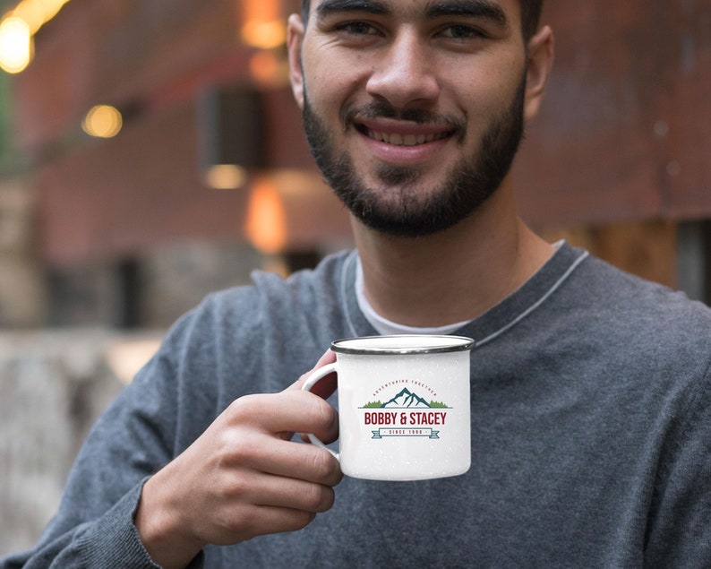 May include: White enamel camping mug with a red, green, and blue logo that says "Lake Fishing Tradition Bobby & Stacey Since 1988".