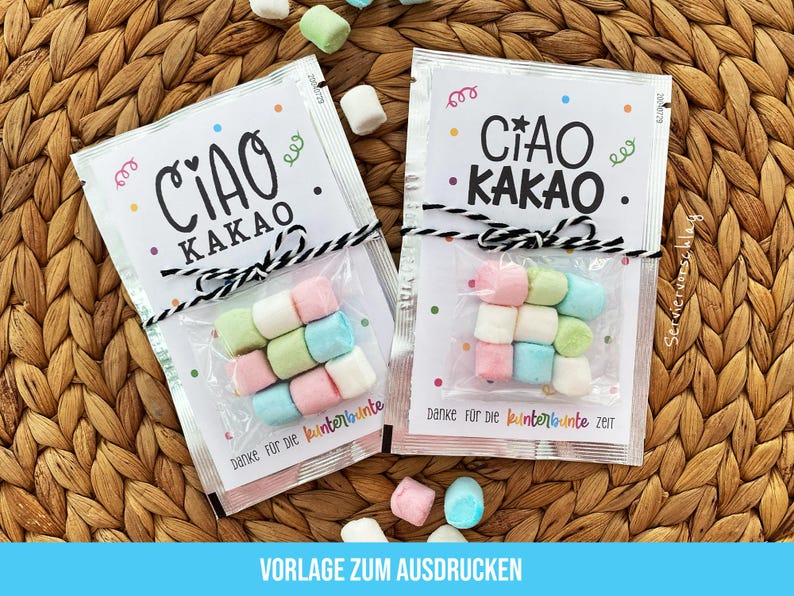 May include: Two small packets of marshmallows, each with a label that reads "CIAO KAKAO" in black script. The packets are tied with black and white twine and contain pastel-colored marshmallows. The background is a woven wicker surface.